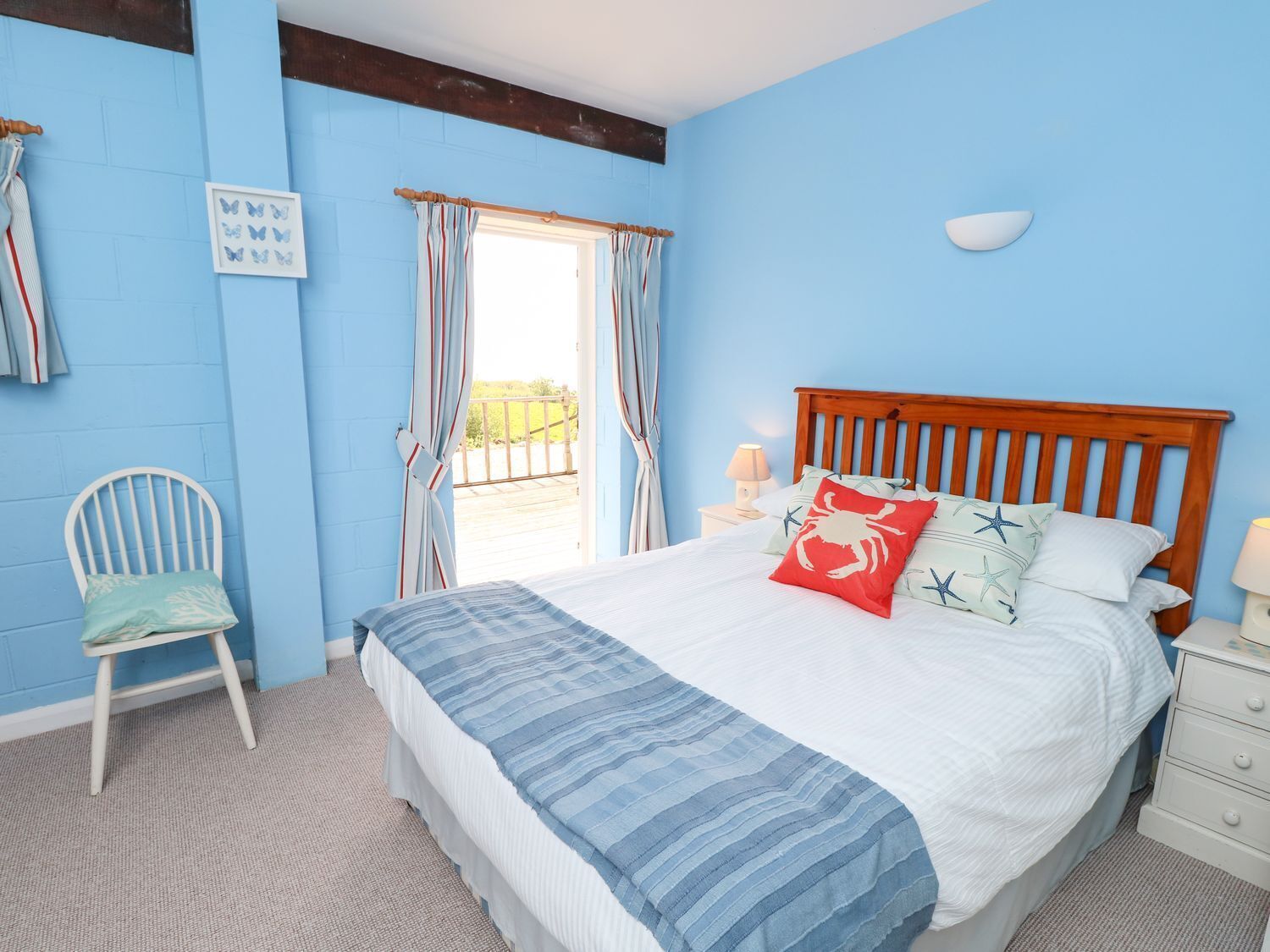 A bedroom with a wooden bed, a chair, a nightstand, and a window with curtains.