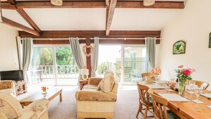 A cozy living room with a sofa, a television, and a dining area with a table set for two. - Swifts (Ventnor)