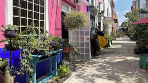 Una calle estrecha con edificios coloridos, macetas con plantas y una motocicleta estacionada.