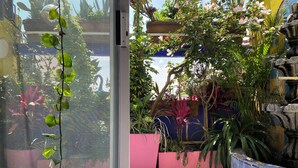 Un patio con suelo de baldosas, plantas en macetas y una fuente decorativa.