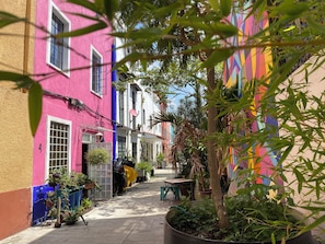Una calle estrecha con edificios coloridos, una motocicleta estacionada y plantas en macetas.