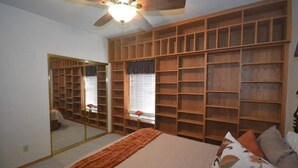 A bedroom with a large bed, a ceiling fan, a wardrobe with multiple shelves, and a mirror. - Riverfront Luxury: 4BR Retreat w/ Dock, Launch, Endless Views, Colorado Oasis (Mohave Valley)