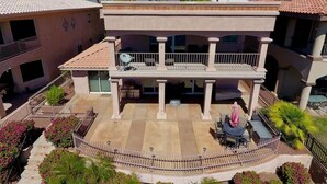A two-story building with a covered patio area, a balcony, and a view of palm trees and mountains. - Riverfront Luxury: 4BR Retreat w/ Dock, Launch, Endless Views, Colorado Oasis (Mohave Valley)