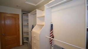 A walk-in closet with open shelving, a wooden door, and a white wall with an American flag. - Riverfront Luxury: 4BR Retreat w/ Dock, Launch, Endless Views, Colorado Oasis (Mohave Valley)