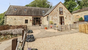 Un bâtiment en pierre avec une allée en gravier et une clôture en bois.