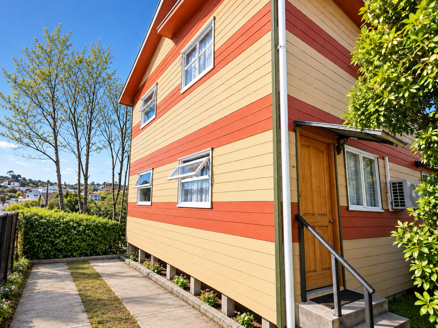 A multi-story house with a red and yellow exterior, a wooden door, and a small front porch with steps.
