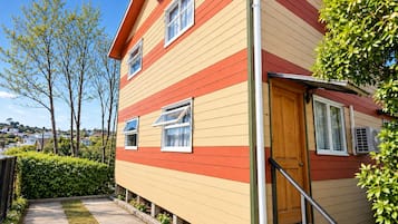 A multi-story house with a red and yellow exterior, a wooden door, and a small front porch with steps.