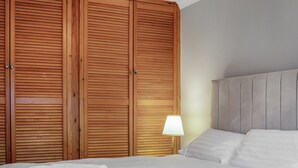 A bedroom with a bed, white linens, a lamp, and wooden wardrobes. - 4 bedroom accommodation in Salisbury, near Dorset (Salisbury, near Dorset)