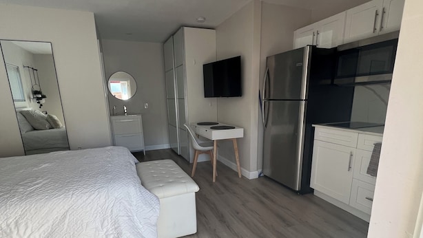 Un dormitorio moderno con cama, escritorio y kitchenette.