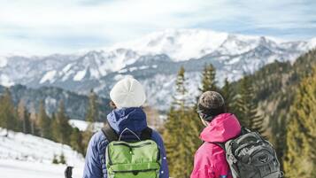 Two people with backpacks on a snowy mountain with a view of snow-covered mountains.