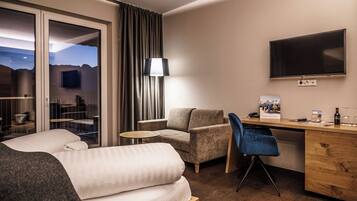 Ein Hotelzimmer mit Bett, Schreibtisch, Stuhl, Lampe und Fernseher.