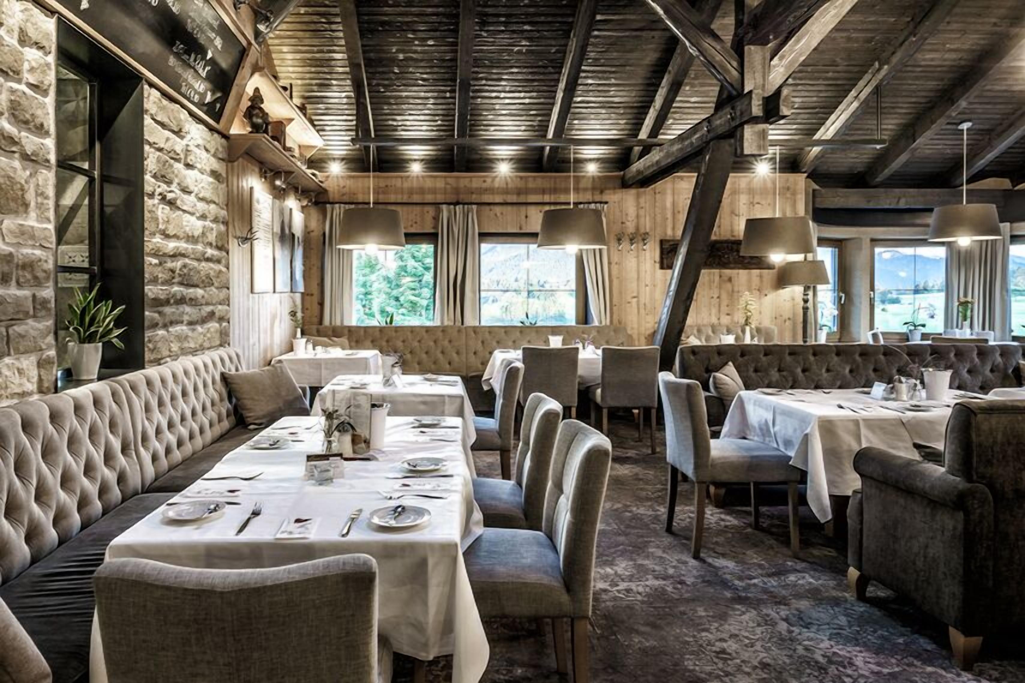 Un restaurante con una larga mesa de comedor, asientos acolchados y una decoración rústica.