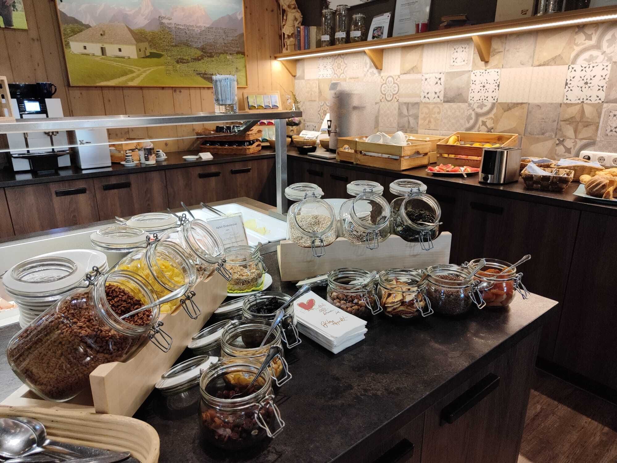 A buffet setup with various food items in jars and containers, a wooden counter, and a tiled backsplash.