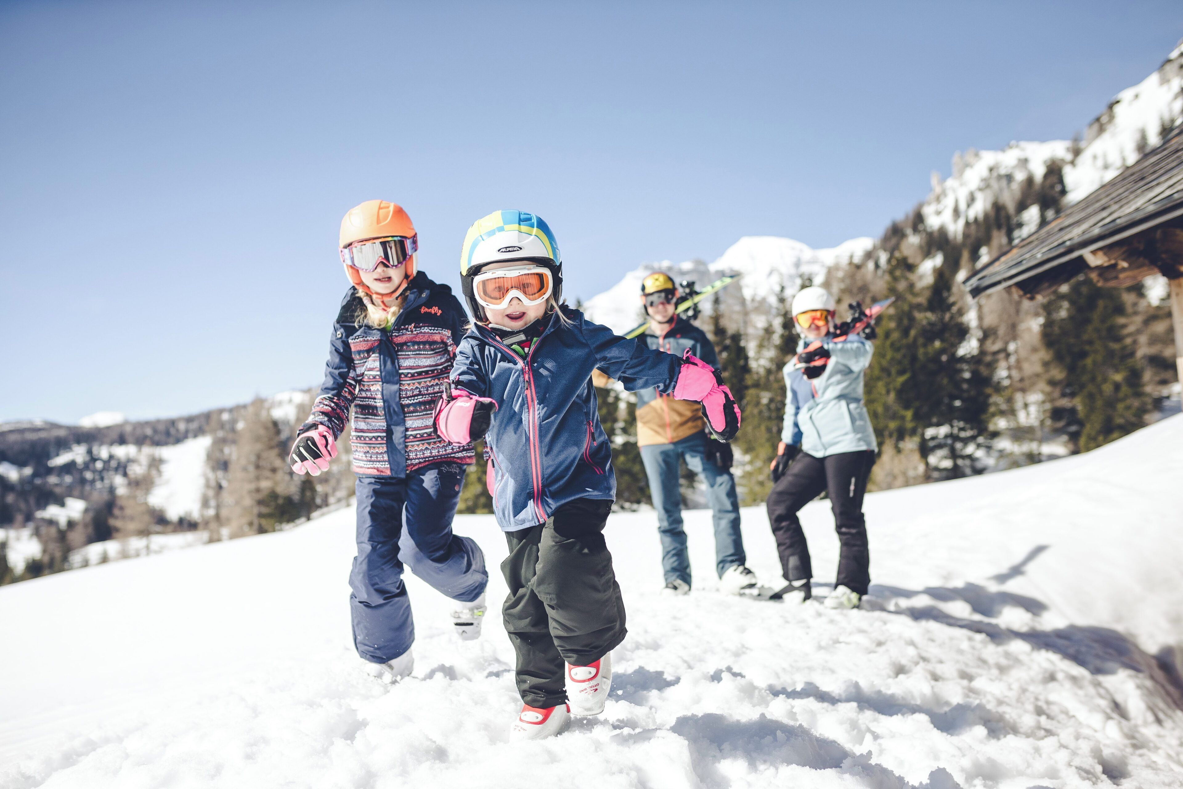 A group of people skiing on a snowy slope with mountains in the background.