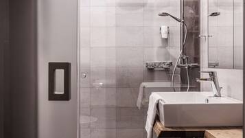 A modern bathroom with a glass shower enclosure, a white sink, and a wooden countertop.