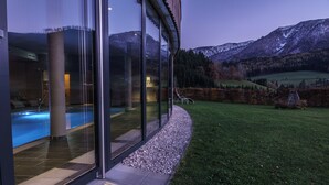 A modern building with large glass windows, a swimming pool, and a view of mountains. - Landhotel das Stocker (Vorderstoder)