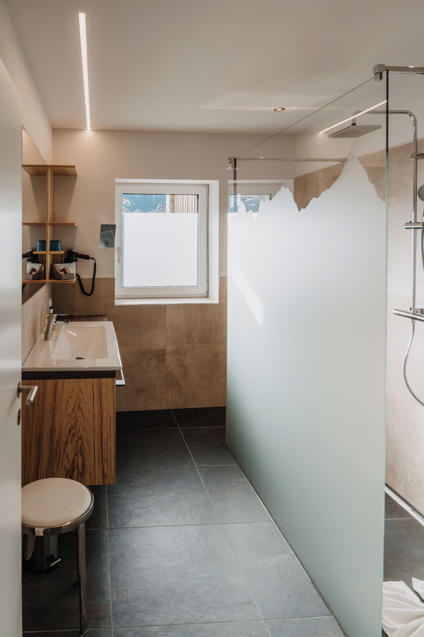 A modern bathroom with a wooden vanity, a sink, a mirror, and a shower enclosure.
