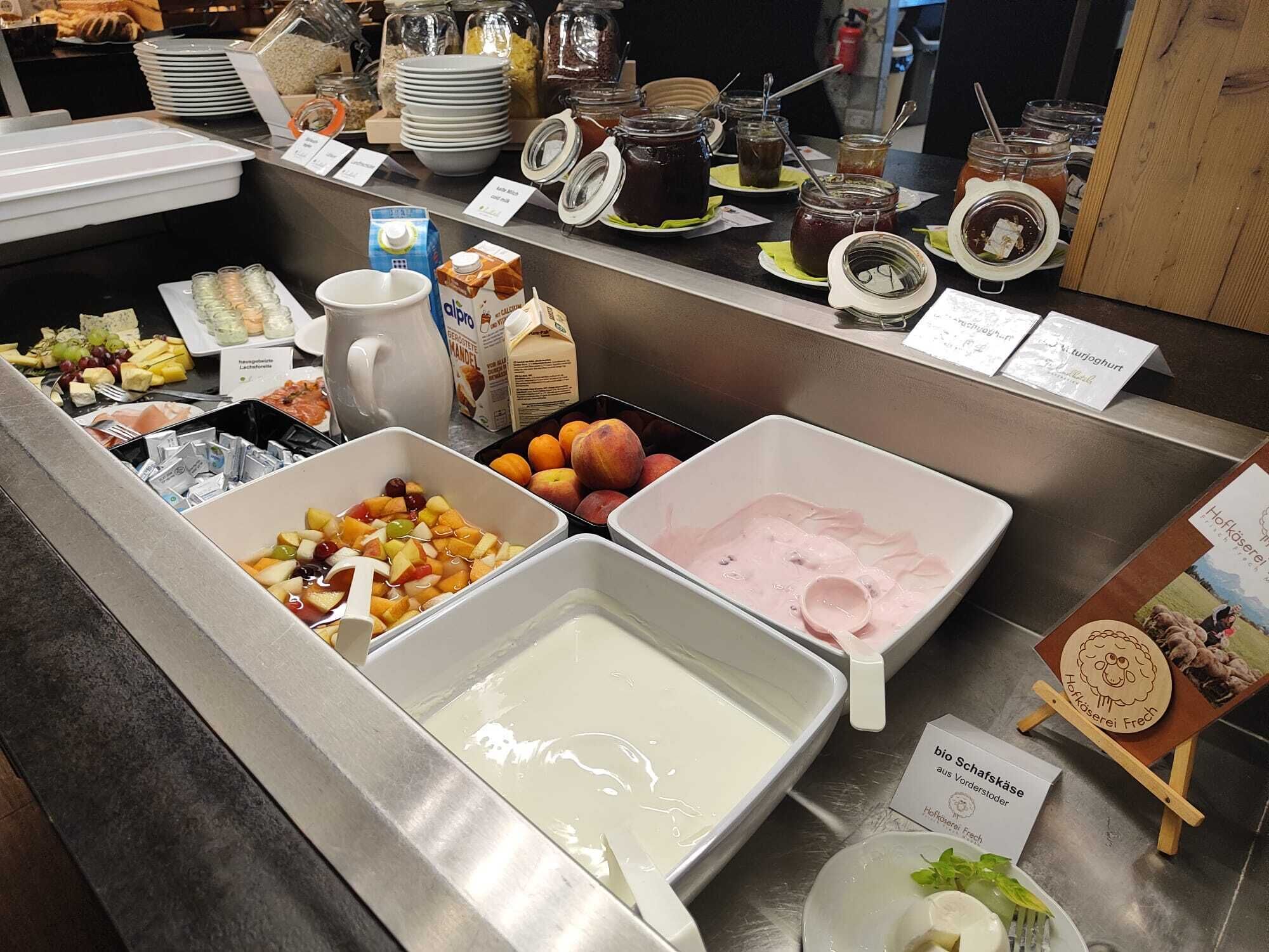 A buffet with various food items including fruits, dairy products, and condiments.