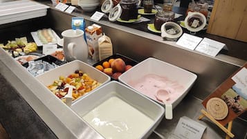 A buffet with various food items including fruits, dairy products, and condiments.
