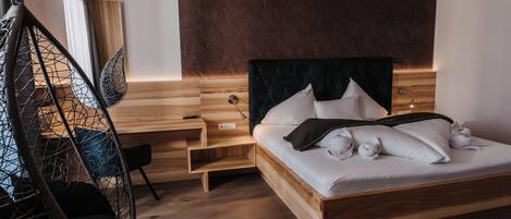A modern bedroom with a wooden bed, a hanging chair, and a wooden nightstand.