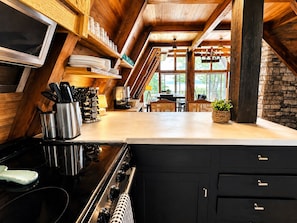 Una cocina con estufa, armarios y una zona de comedor con mesa y sillas.