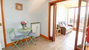 Une pièce confortable avec une petite table et deux chaises, un réfrigérateur et un lit donnant sur une belle vue.
