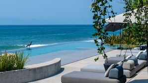 Zona de piscina con sillones de descanso y vista al océano.
