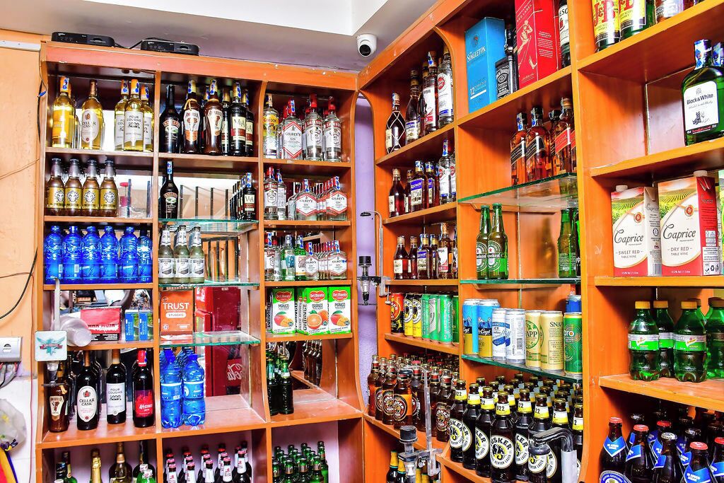 Una licorería con estantes repletos de diversas bebidas alcohólicas y aperitivos.