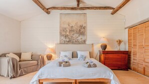 Une chambre à coucher comprenant un lit, des tables de chevet, une commode, un canapé et un plafond en bois.