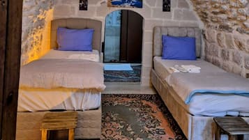 A cozy room with two beds, a wooden bench, and a patterned rug.