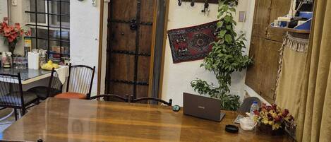 A traditional room with a wooden table, four chairs, a laptop, and a potted plant.