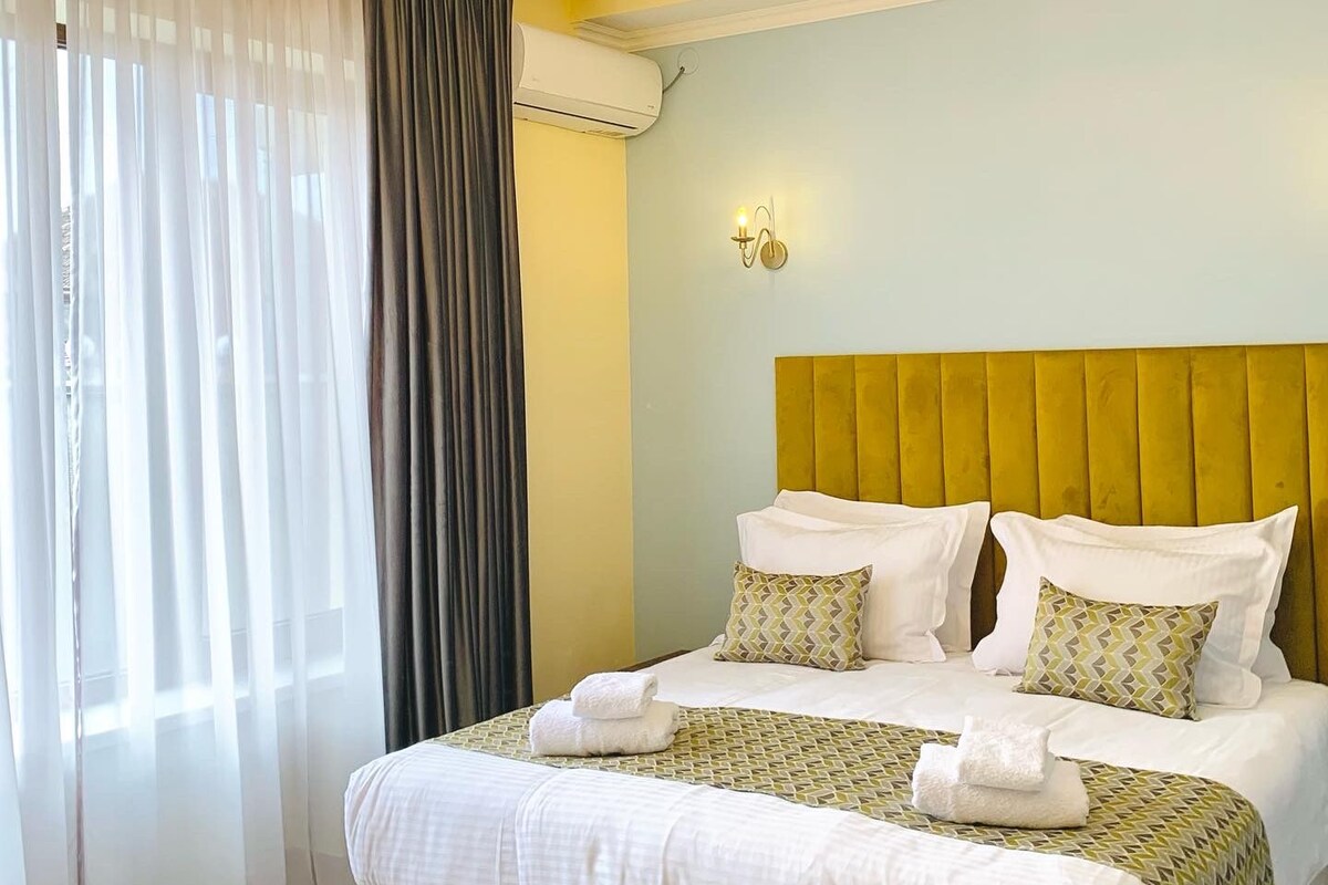 Une chambre d’hôtel avec un grand lit, une tête de lit et un lustre.