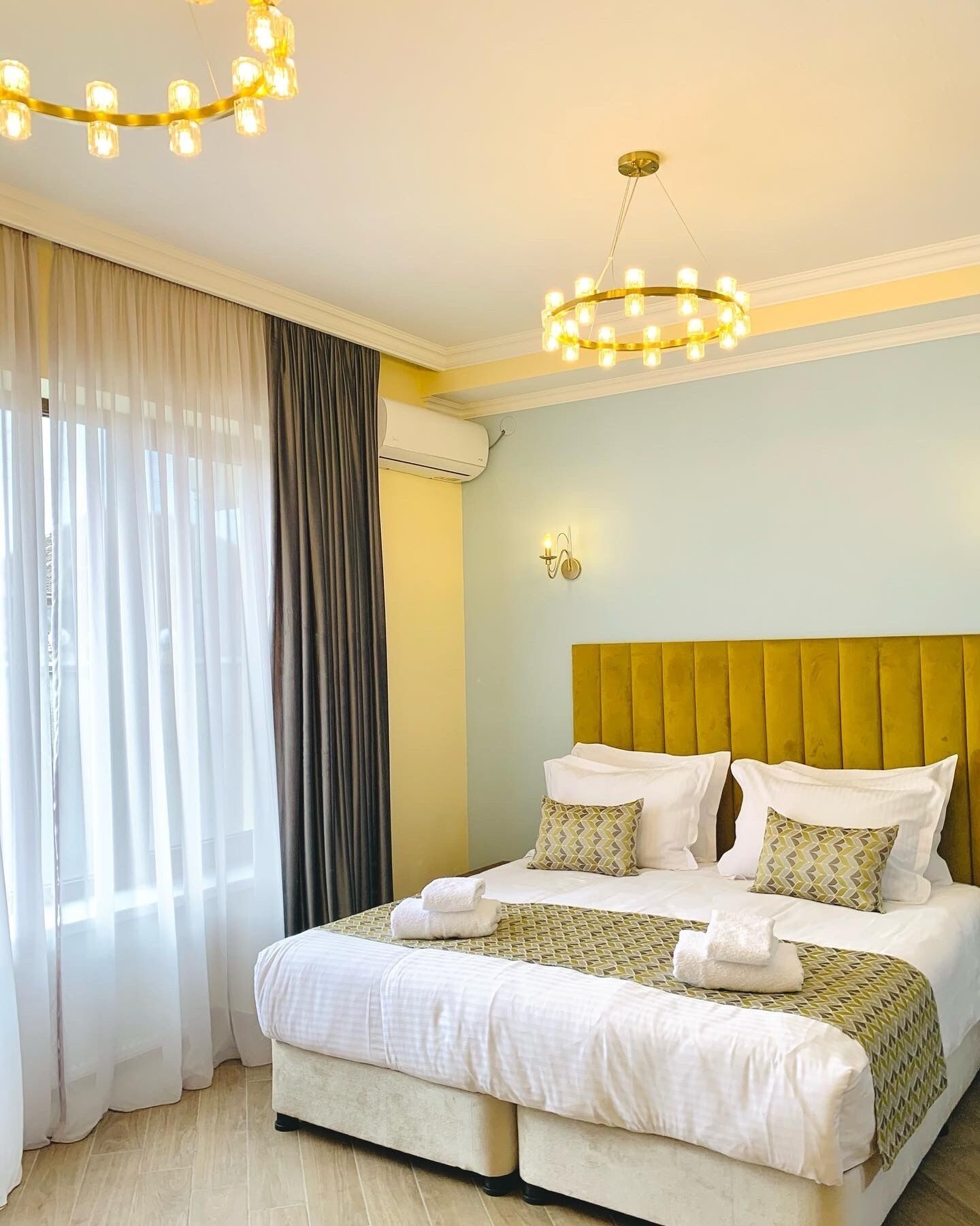 A hotel room with a large bed, a headboard, and a chandelier.