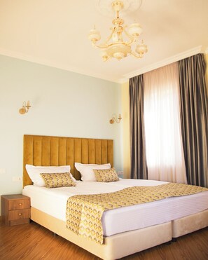 Una habitación de hotel con una cama grande, cabecera de madera y una araña.