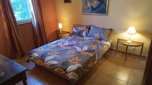 Ein Schlafzimmer mit einem Bett, zwei Nachttischen, einem Fenster mit Vorhängen und einem Bild an der Wand.