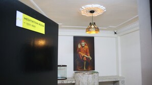 A meditation room with a sign, a hanging light fixture, a framed painting, and a small table with yoga mats.