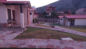 Un patio con senderos de piedra, un banco y edificios con techos de tejas rojas.