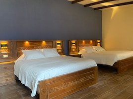 Habitación de hotel con dos camas de madera, cada una con cabecero de diseño geométrico e iluminación integrada.
