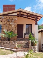 Una casa de dos pisos con fachada de piedra, una puerta marrón y un pequeño porche con escalones que conducen a la entrada.