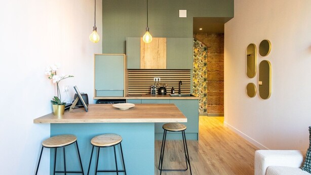 A compact kitchen with a wooden island, bar stools, pendant lights, and a small potted orchid. - Lassagne - 2 - New studio in the city center (Lyon)