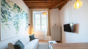 A modern living room with a sofa, a TV mounted on the wall, and a wooden ceiling. - Lassagne - 2 - New studio in the city center (Lyon)