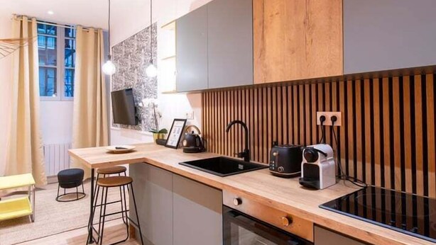 Une cuisine moderne dotée d’un plan de travail en bois, d’un four encastré et de tabourets de bar.