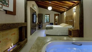 Une chambre confortable avec un grand lit, un plafond en bois, une cheminée et une baignoire.