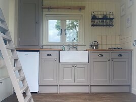 A kitchen with white cabinets, a built-in sink, a window, and a kettle on the countertop.