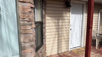 A house with a stone exterior, a wooden door, and a porch with a chair.