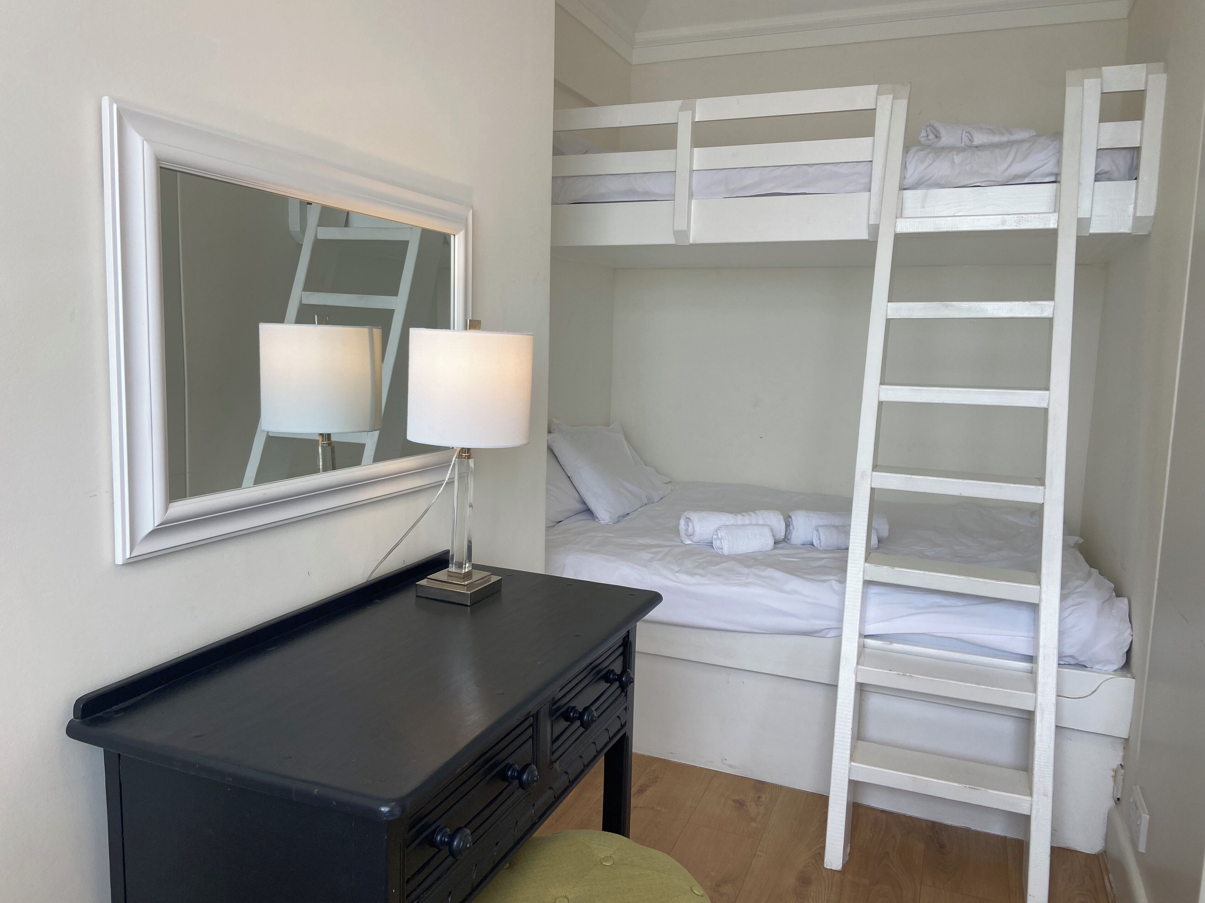 Una camera con letto a castello, uno specchio, un comodino e una lampada.