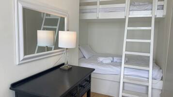 Una camera con letto a castello, uno specchio, un comodino e una lampada.