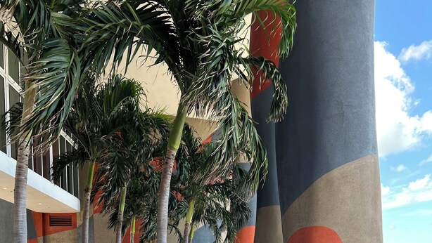 A modern outdoor lounge area with two sun loungers, a low wall with greenery, and a large pillar with a geometric design. - Ocean View Luxury Studio @ Brickell-DWTN Miami (Miami)