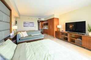 Ein Hotelzimmer mit einem großen Bett, einer Couch, einem Fernseher und einer Küchenzeile.