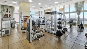 A gym with various exercise machines, large windows, and a view of the city. - Ocean View Luxury Studio @ Brickell-DWTN Miami (Miami)